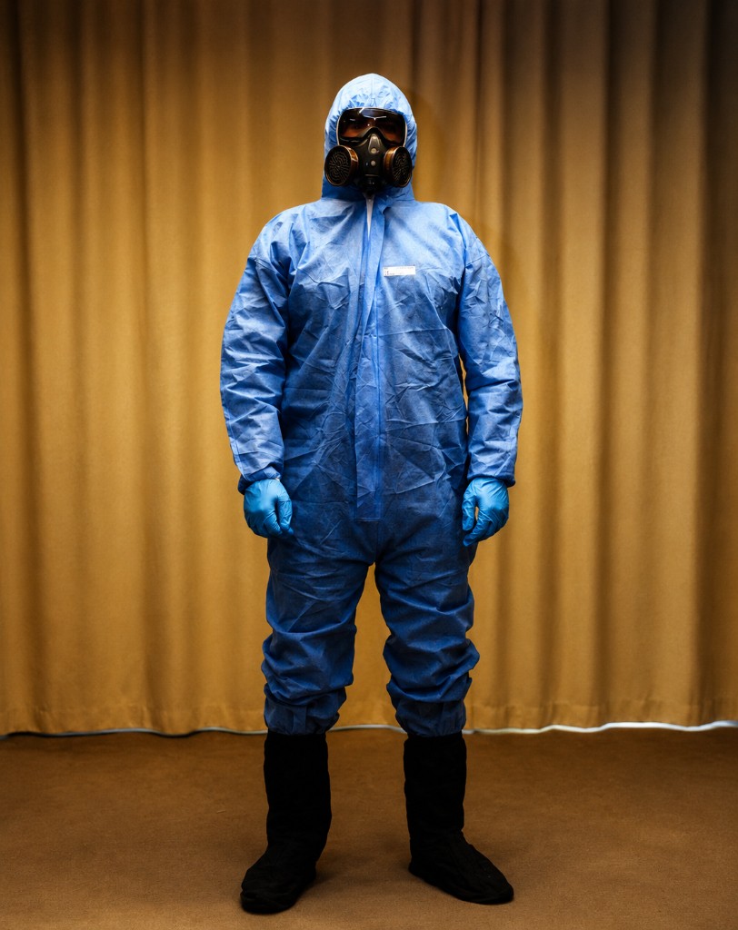 Person in full blue protective coverall suit with respirator mask and boots